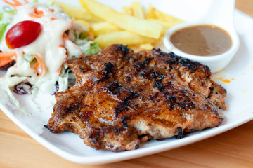 Chicken steak is a fast food, chicken steak this dish consists of with salad which has purple lettuce carrot tomato salad dressing french fries and black pepper sauce all in a white plate.