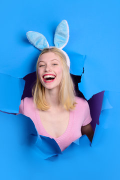 Easter Day. Woman looking through paper. Happy easter! Smiling girl with bunny ears. Easter. Bunny. Easter hunt. Bunny ears. Breaking paper. Sale. Discount. Spring.