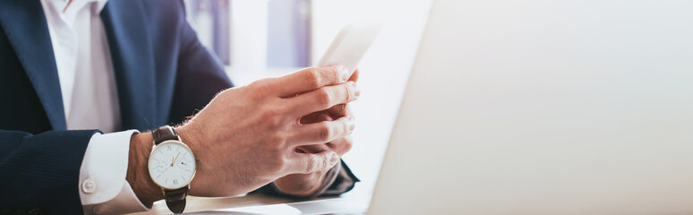 selective focus of man using smartphone at workplace with copy space