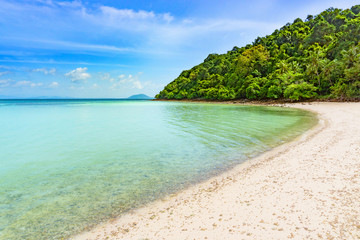 Fototapeta na wymiar Blue sea and white sand beach with moutain