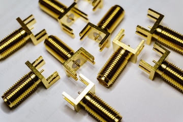 Close-up of scattered gold plated SMA male connectors electronics components on white background in random pattern