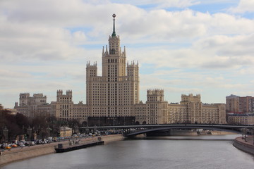 Fototapeta na wymiar High-rise building on Kotelnicheskaya embankment, river and bridge in Moscow - view from the floating bridge in early spring in Russia