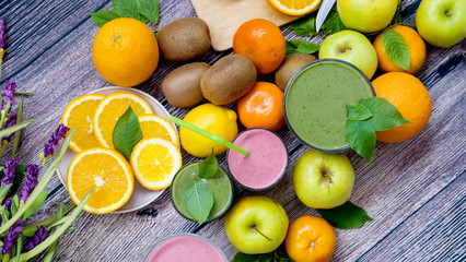 Fresh juicy fruit and green cocktail on a wooden background with a cutting board and knife. View from above