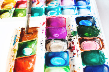 watercolor palette, the child draws with paints
