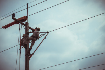 Two linemans use devices that are insulated for maintenance high voltage distribution system. To...