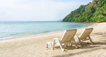 Two empty chair on beach with forest mountain