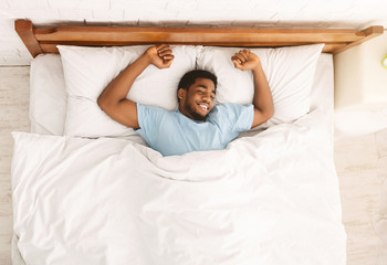 Young african-american man sleeping in bed top view