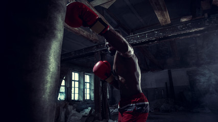 Hands of boxer over dark gym background. Strength, attack and motion concept. Fit african american...
