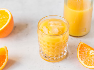Orange fresh juice with ice cubes in a glass on a table. The concept of healthy eating.