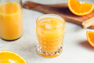 Orange fresh juice with ice cubes in a glass on a table. The concept of healthy eating.