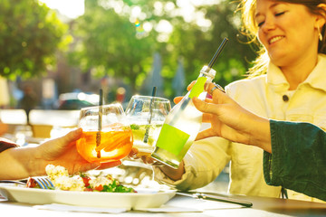 leisure, holidays, eating, people and food concept - happy friends having dinner  and clinking...