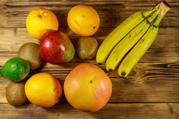 Assortment of tropical fruits on wooden table. Still life with bananas, mango, oranges, avocado, grapefruit and kiwi fruits