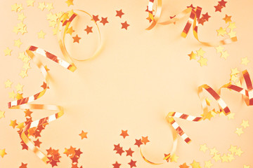 Background about a party, confetti, stars and streamers. Made in gold shades. Copy space. Top view