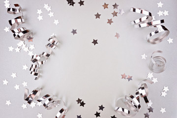 Background about a party, confetti, stars and streamers. Made in silver shades. Copy space. Top view