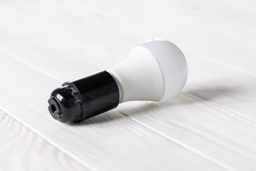 LED light in a dark base. Lies on a wooden background. white color.