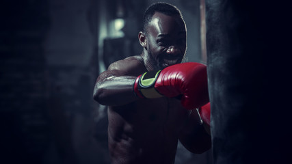 Hands of boxer over dark gym background. Strength, attack and motion concept. Fit african american...