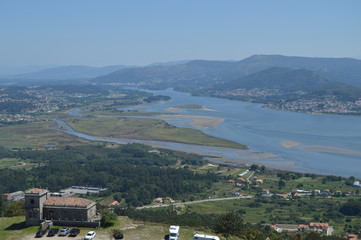 Fototapeta na wymiar The Miño River, Forest House And Portuguese Village Of Caminha From The Castro Of Santa Tecla In The Guard. Architecture, History, Travel. August 15, 2014. La Guardia, Pontevedra, Galicia, Spain.
