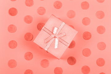 Beautiful little gift box with silky ribbon on coral background with carefully arranged round paper...