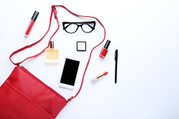 Handbag with cosmetics, smartphone and glasses on white background