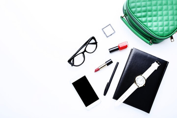 Handbag with cosmetics, smartphone, glasses and wrist watch on white background