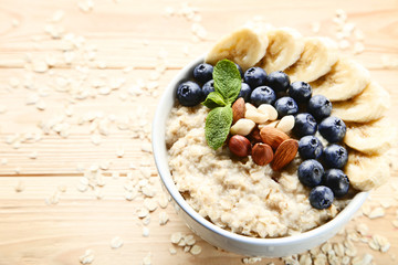 Oatmeal with berries and nuts in bowl on wooden table