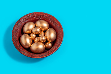 golden eggs in a clay plate on a blue background