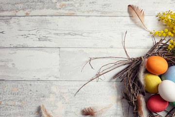 Colorful Easter eggs in nest on wooden table