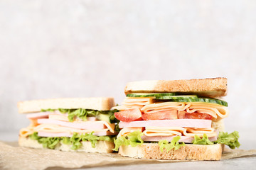 Sandwiches with ham and vegetables on grey background
