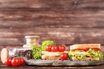 Tasty sandwich with fresh vegetables and pepper spices on brown wooden table