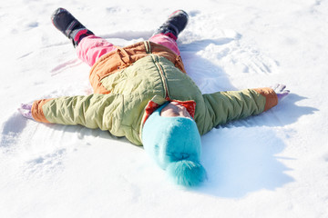 little girl draws on the snow angel. shallow depth of field.
