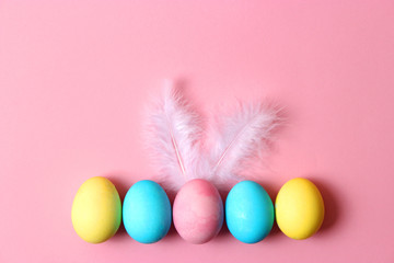  Easter composition of painted eggs and feathers on a colored background. Easter background