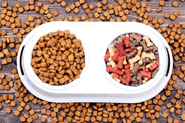 Dry pet food in bowl on brown wooden table