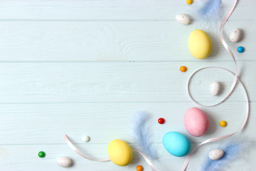  Easter composition of painted eggs and feathers on wooden background. Background for Easter, a place to insert text