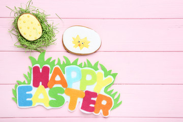 Text Happy Easter with gingerbread cookies on pink wooden table