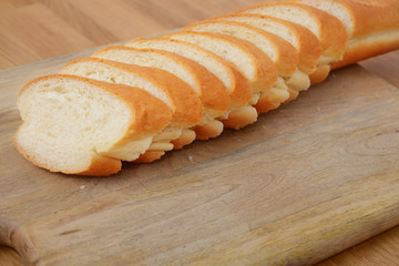 Sliced french bread on cutting board on wooden table