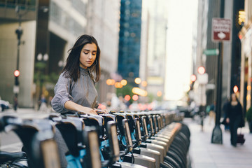 Naklejka premium girl renting a city bike from a bike stand in chicago