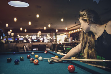 Beautiful woman with long hair playing billiard