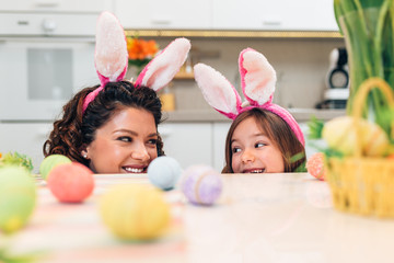 Mother and her cute little daughter having fun in kitchen while preparing Easter eggs.