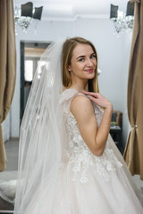 Naklejka premium Beautiful young bride posing in wedding dress in salon