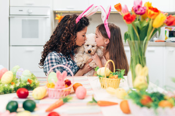 Fototapeta na wymiar Mother and daughter enjoying with their poodle dog, while preparing for Easter.