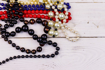 Different beads necklaces on white wooden background