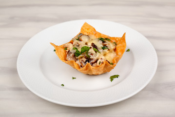 Snack with mushrooms baked in the dough with cheese on a white plate.
