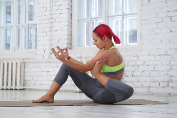 A girl with pink hair practices yoga.