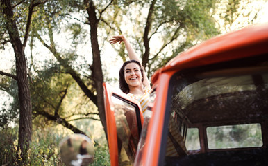 A young girl on a roadtrip through countryside, waving at somebody from a car.