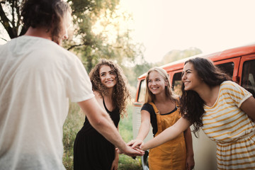 A group of young friends on a roadtrip through countryside, putting hands together.