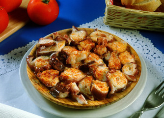 Pulpo con salsa picante, servido en un plato de madera al estilo gallego.