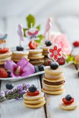 Fruit, berry and pancake canapes on white wooden table