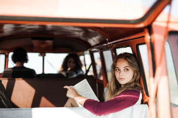 A group of young friends on a roadtrip through countryside, a girl reading a book.