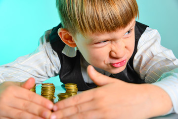 An angry and greedy little boy hides his cash savings. The greedy and vicious concept of wealth...