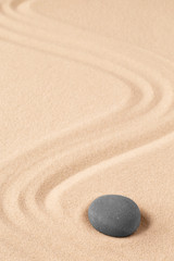 Spa wellness for inner life and spiritual health. Zen meditation stone for relaxation. Concept for purity balance and harmony. Background with raked sand and open copy space.